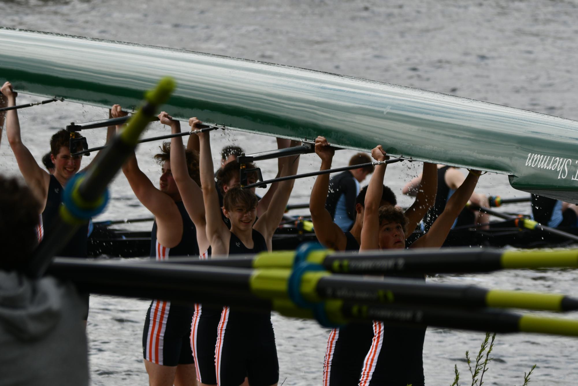 Rowers carrying their shell out of the water. Photo courtesy of ETHS rowing team.