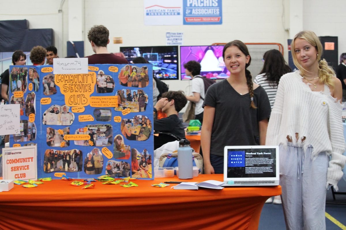 Maija Ahleman and Sophie Kegler stand beside their Community Service table at the Activities Fair.